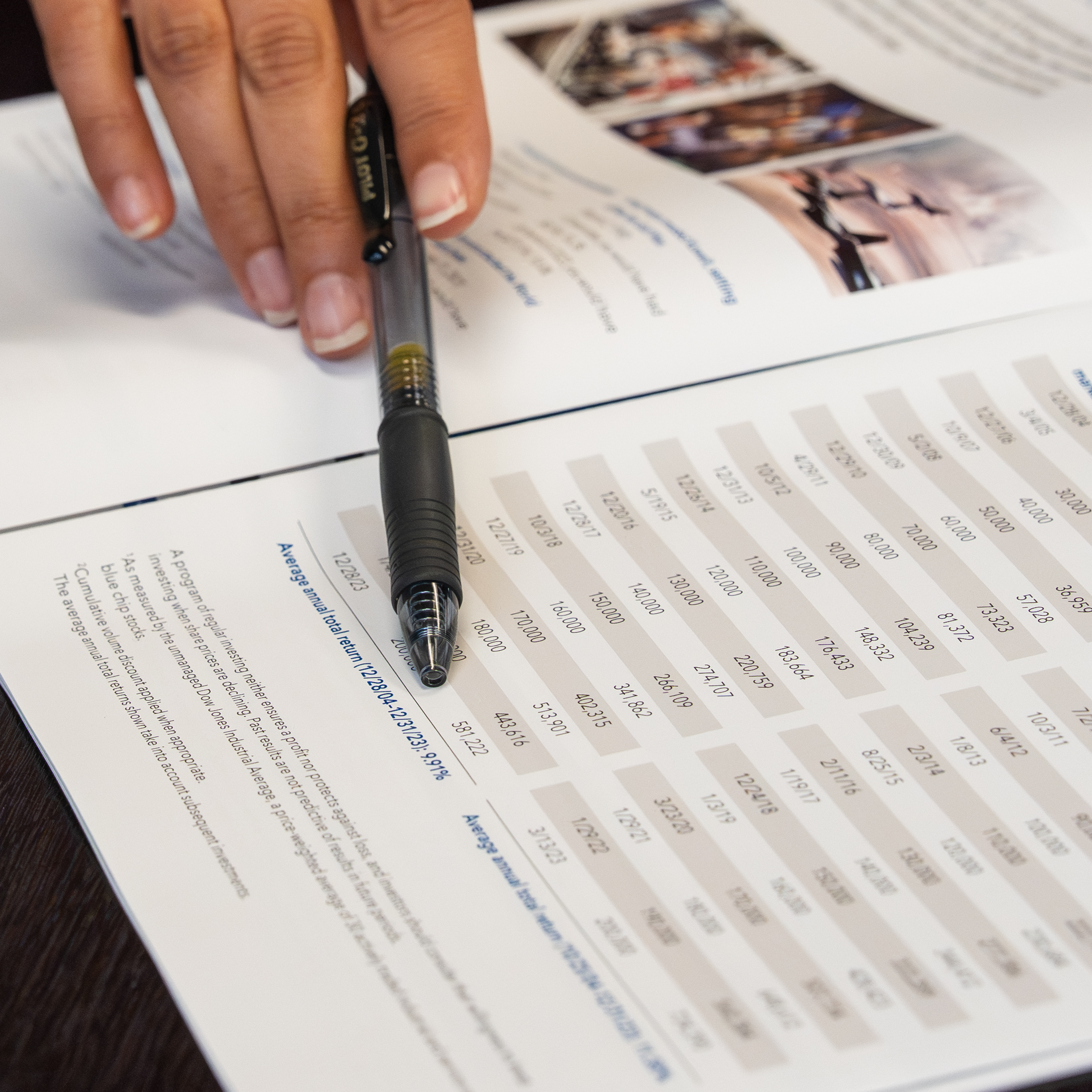 person holding a pencil and pointing at a financial paper