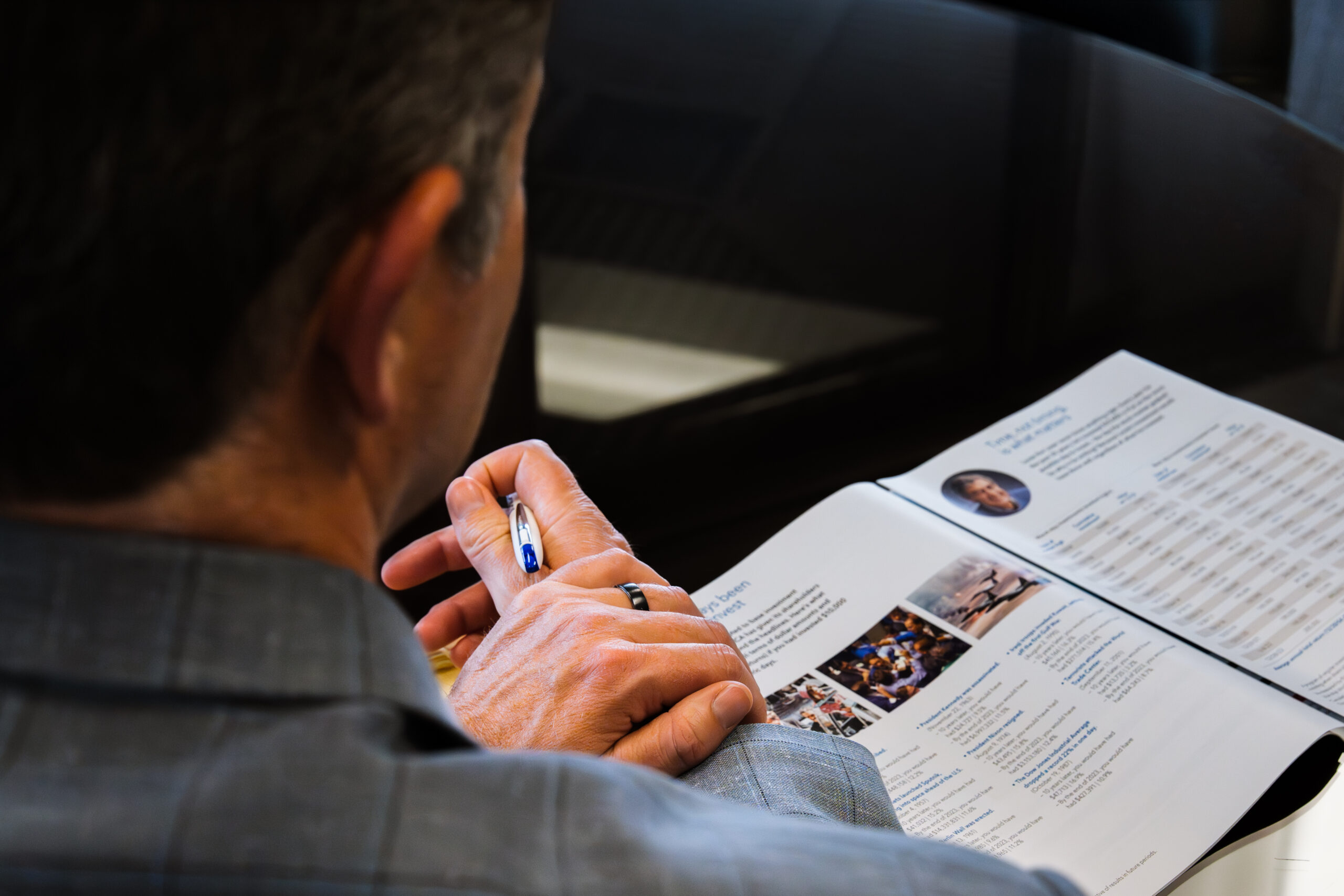 person holding a pencil looking at a financial paper
