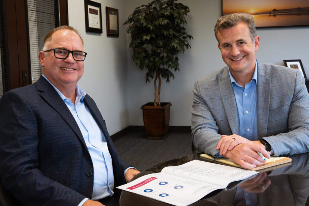 two people sitting at a desk looking at the camera